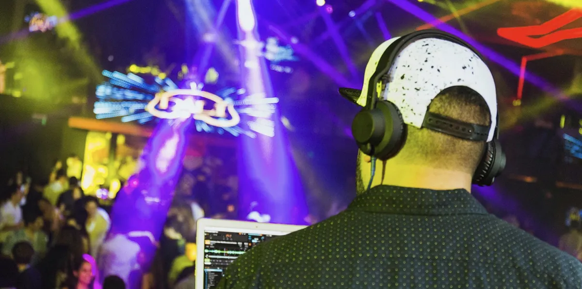 DJ Paul en cabina de Dalí — vista desde atrás con luces y pista llena